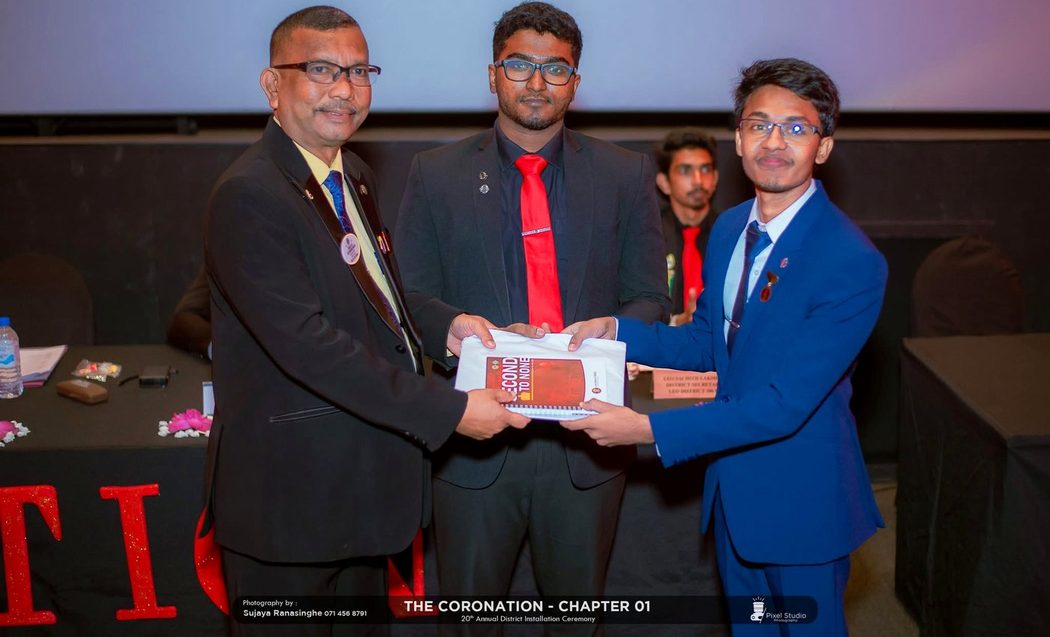 Kusal Nirmala being presented with materials on stage at a Leo District installation ceremony